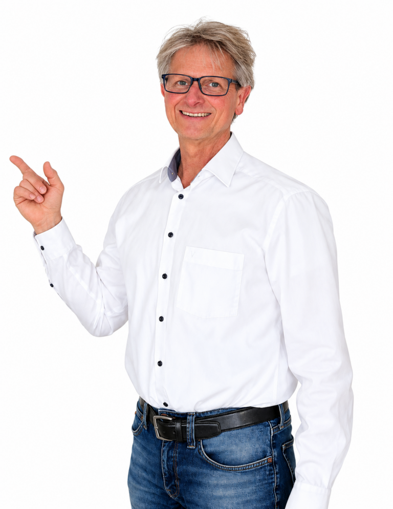 Andreas Scherer steht vor einer weißen Wand und zeigt mit dem Finger etwas